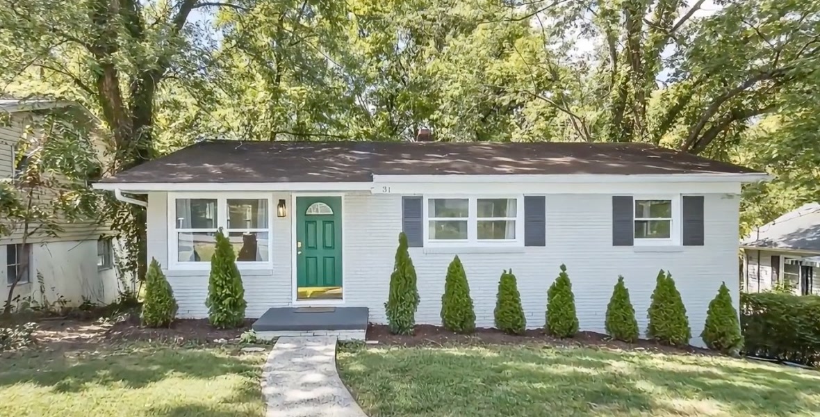 White brick ranch with a green door and new shrubs. Listing still, 31 Wilmington Rd, Asheville.